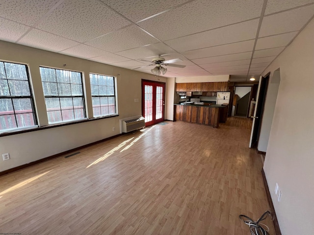 unfurnished living room with french doors, a paneled ceiling, ceiling fan, hardwood / wood-style flooring, and an AC wall unit