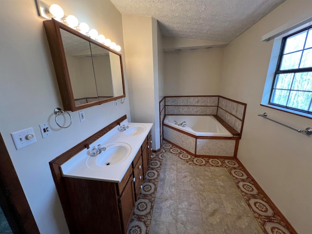 bathroom featuring vanity, a textured ceiling, a relaxing tiled tub, and tile patterned flooring