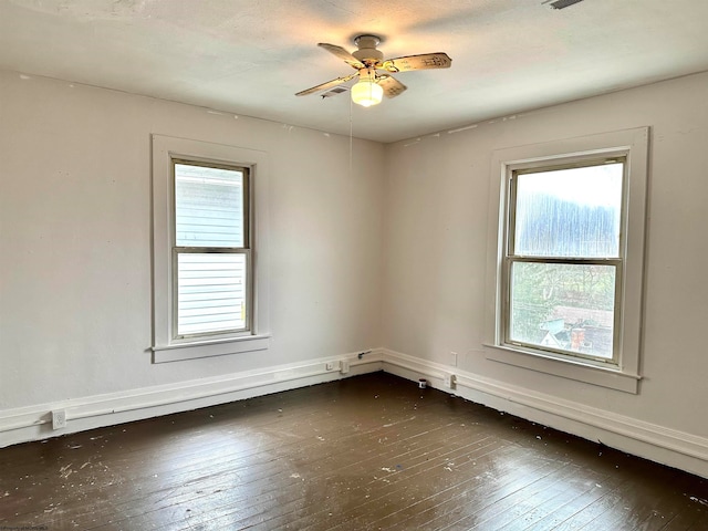 spare room with plenty of natural light, dark wood-type flooring, and ceiling fan