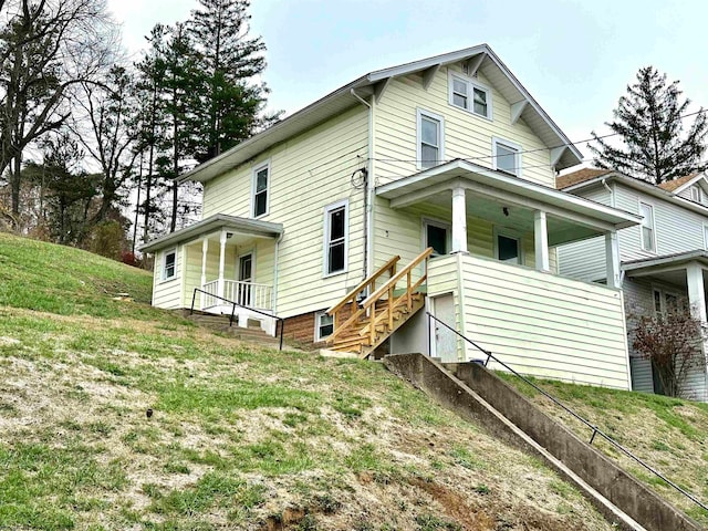 back of property featuring a yard and covered porch