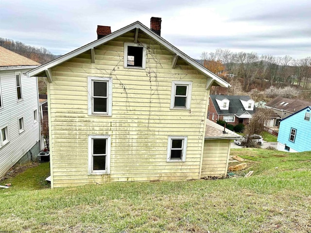 rear view of property with a yard and central AC