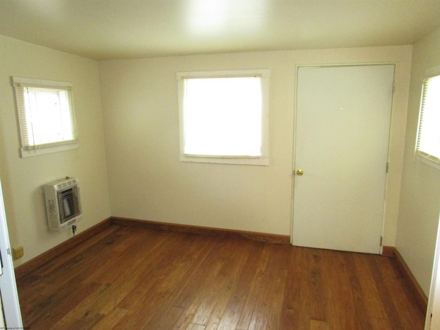 empty room featuring heating unit and dark wood-type flooring