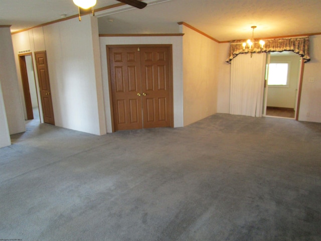 carpeted spare room featuring ceiling fan with notable chandelier and ornamental molding