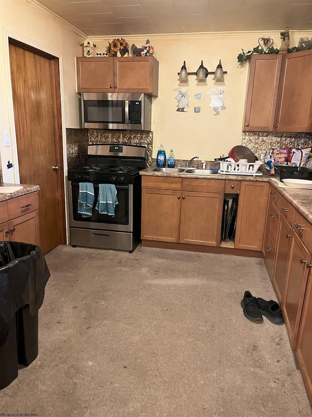 kitchen with backsplash, sink, ornamental molding, appliances with stainless steel finishes, and light colored carpet