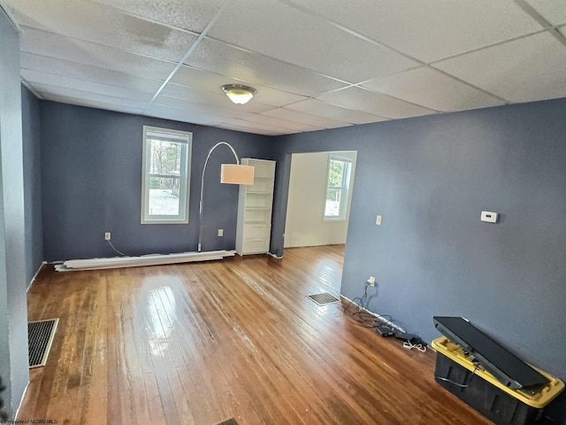 unfurnished room with a paneled ceiling, plenty of natural light, and wood-type flooring