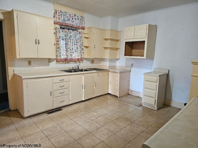 kitchen featuring cream cabinetry, light tile patterned floors, ornamental molding, and sink