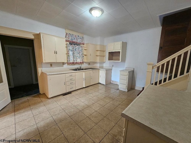 kitchen with crown molding, sink, and light tile patterned floors