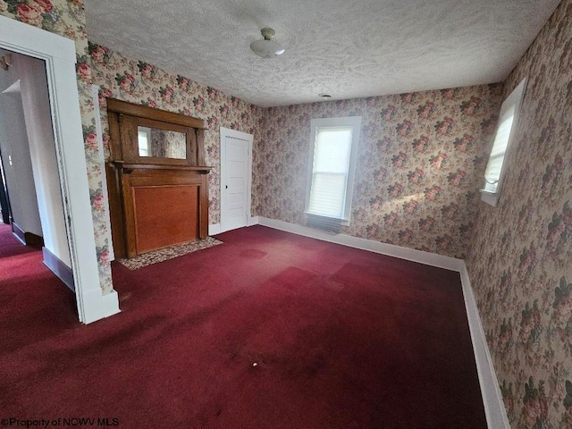 unfurnished living room with dark carpet and a textured ceiling