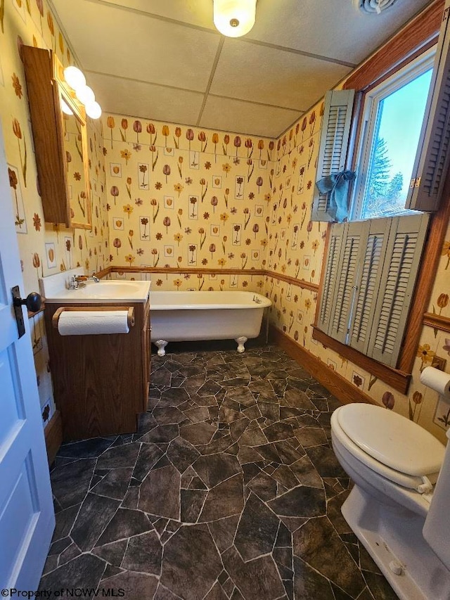 bathroom featuring a bathing tub, a drop ceiling, vanity, and toilet