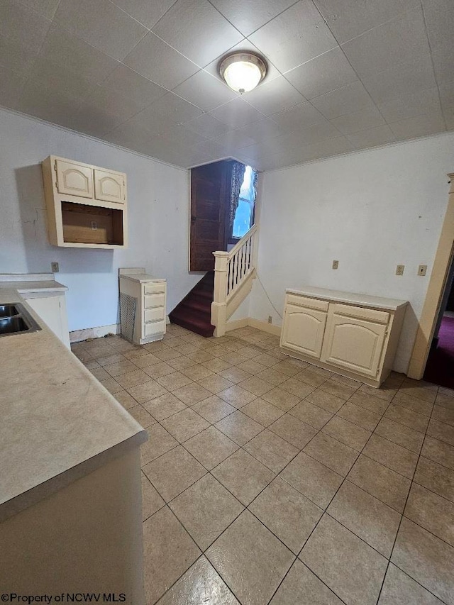 interior space with cream cabinets, sink, and light tile patterned flooring