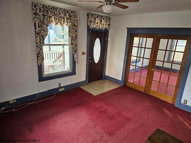 carpeted foyer entrance with ceiling fan, french doors, a healthy amount of sunlight, and ornamental molding