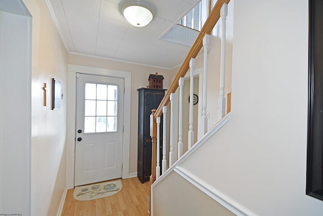 entryway with light hardwood / wood-style flooring and crown molding