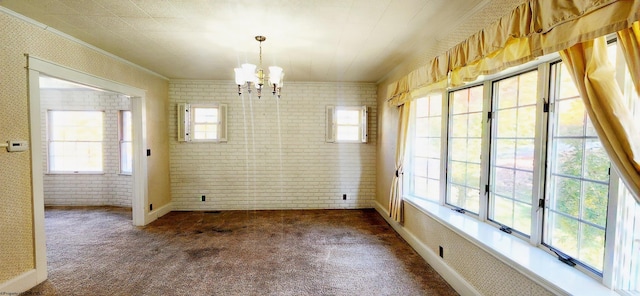 unfurnished dining area featuring dark colored carpet, a notable chandelier, crown molding, and brick wall