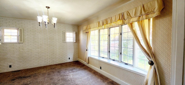 spare room with dark colored carpet, brick wall, and an inviting chandelier