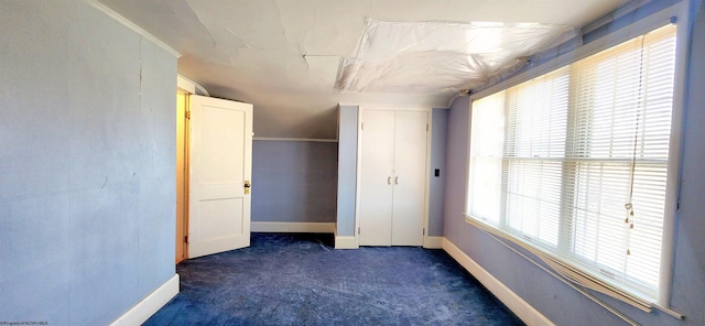 unfurnished bedroom featuring dark carpet and multiple windows