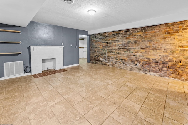 unfurnished living room with light tile patterned floors, a textured ceiling, and brick wall