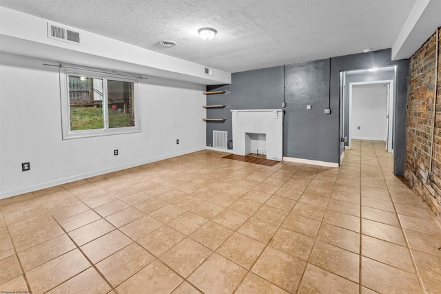 unfurnished living room with light tile patterned floors, a textured ceiling, a brick fireplace, and brick wall