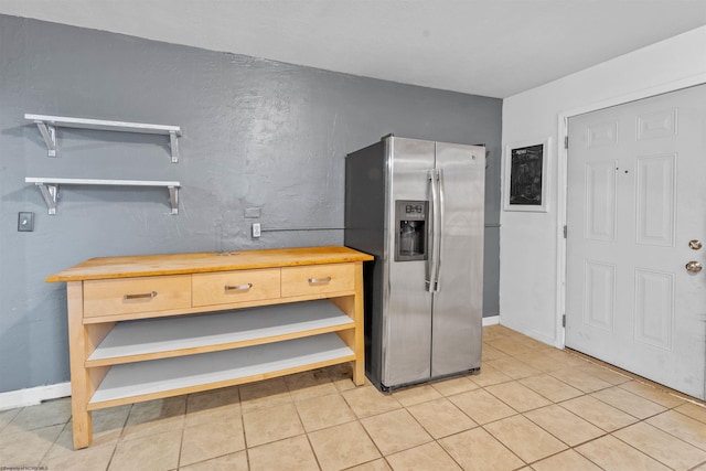 kitchen with stainless steel fridge with ice dispenser, light tile patterned flooring, and wood counters