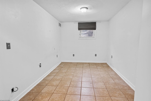 spare room featuring light tile patterned floors and a textured ceiling