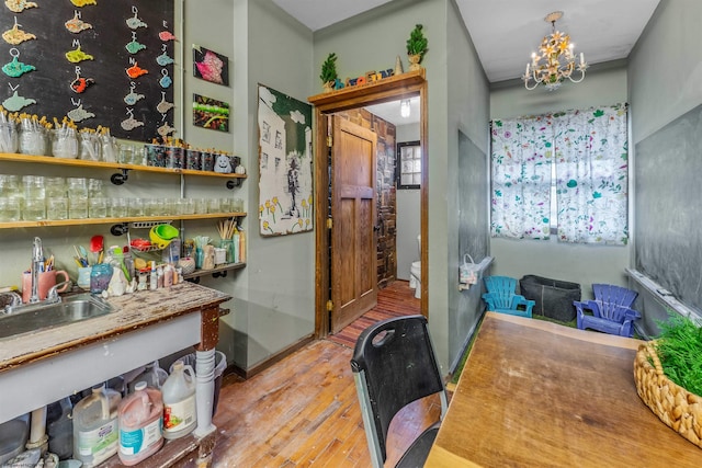 bar with hardwood / wood-style floors, sink, and a chandelier