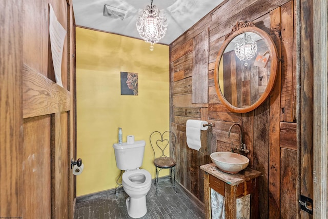 bathroom with an inviting chandelier, toilet, and sink