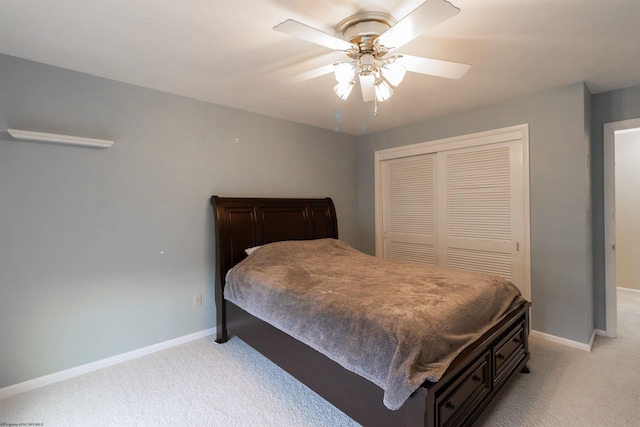 bedroom with ceiling fan, light colored carpet, and a closet