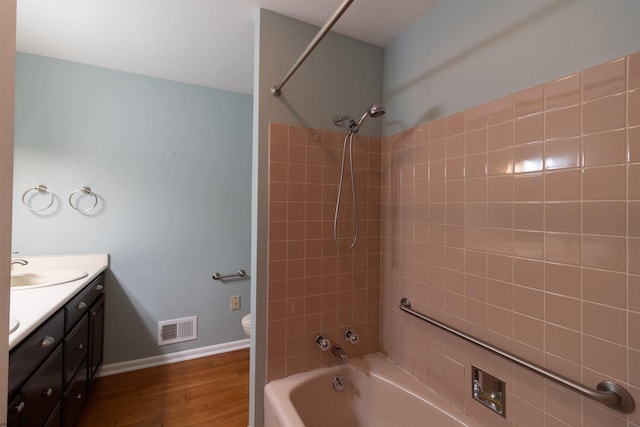 full bathroom featuring toilet, vanity, wood-type flooring, and tiled shower / bath