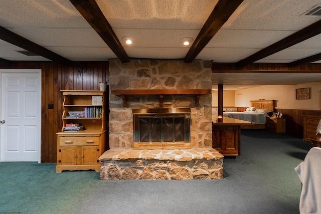 living room with beam ceiling, a fireplace, wood walls, and carpet flooring