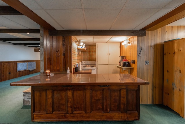 kitchen featuring beamed ceiling, dark carpet, range with electric stovetop, and wooden walls