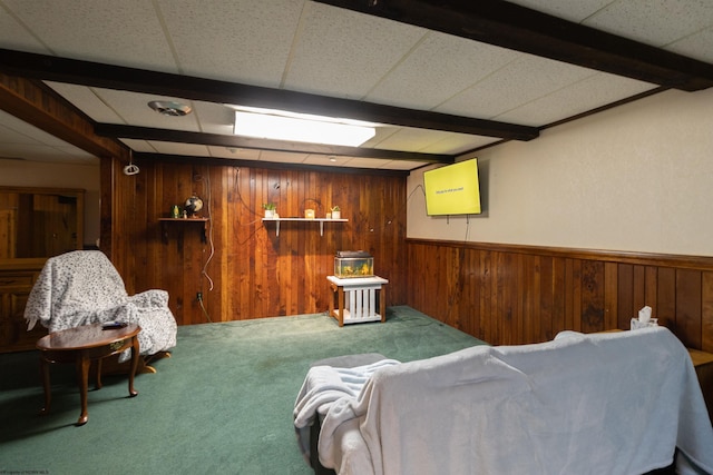 living area featuring carpet flooring, wooden walls, a drop ceiling, and beamed ceiling