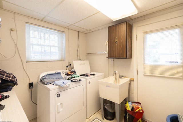 clothes washing area featuring cabinets, washer and clothes dryer, and plenty of natural light