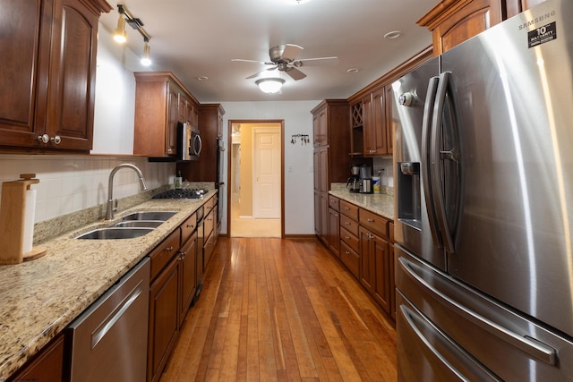 kitchen featuring sink, light stone countertops, stainless steel appliances, and dark wood-type flooring