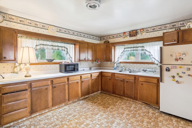 kitchen with a wealth of natural light, sink, and white fridge