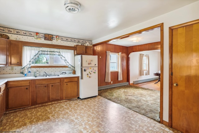 kitchen featuring white refrigerator, a baseboard radiator, backsplash, and sink