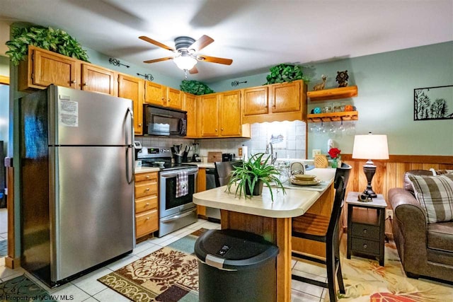 kitchen with appliances with stainless steel finishes, backsplash, a kitchen island, a breakfast bar area, and light tile patterned flooring