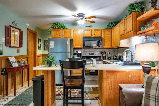 kitchen featuring kitchen peninsula, appliances with stainless steel finishes, light tile patterned floors, and sink