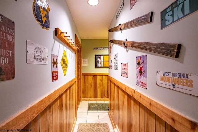 hall featuring light tile patterned flooring and wooden walls