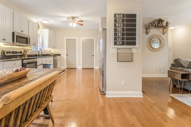 kitchen featuring appliances with stainless steel finishes, light wood-type flooring, ceiling fan, sink, and white cabinets