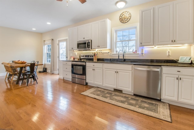 kitchen featuring light wood-type flooring, stainless steel appliances, white cabinetry, and plenty of natural light