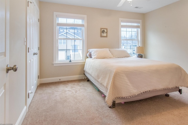 carpeted bedroom featuring multiple windows and ceiling fan