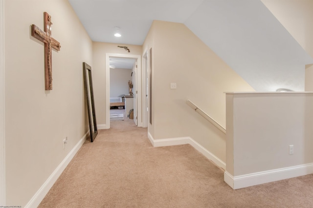 hall featuring light colored carpet and lofted ceiling