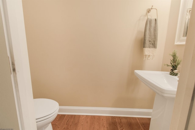 bathroom with wood-type flooring, toilet, and sink