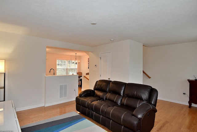 living room with light hardwood / wood-style floors, an inviting chandelier, and sink