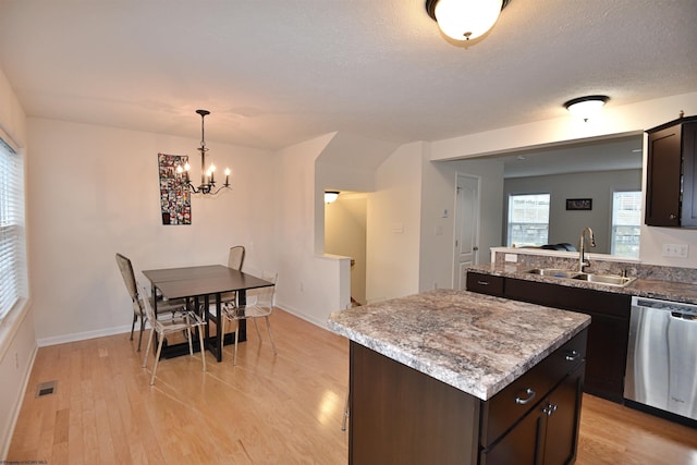 kitchen featuring dark brown cabinetry, dishwasher, sink, an inviting chandelier, and light hardwood / wood-style floors