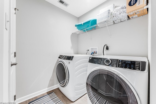 laundry area with hardwood / wood-style floors and independent washer and dryer