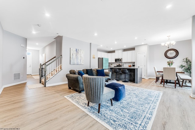 living room with a notable chandelier and light hardwood / wood-style floors