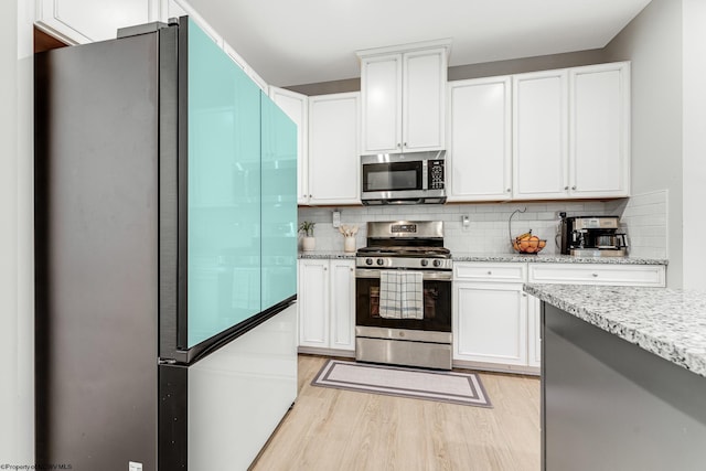 kitchen with light wood-type flooring, stainless steel appliances, and white cabinetry