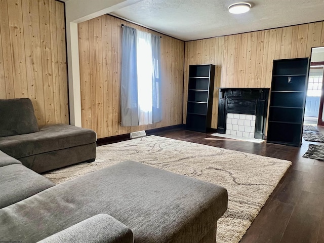 living room with wood walls, dark hardwood / wood-style flooring, a healthy amount of sunlight, and a textured ceiling