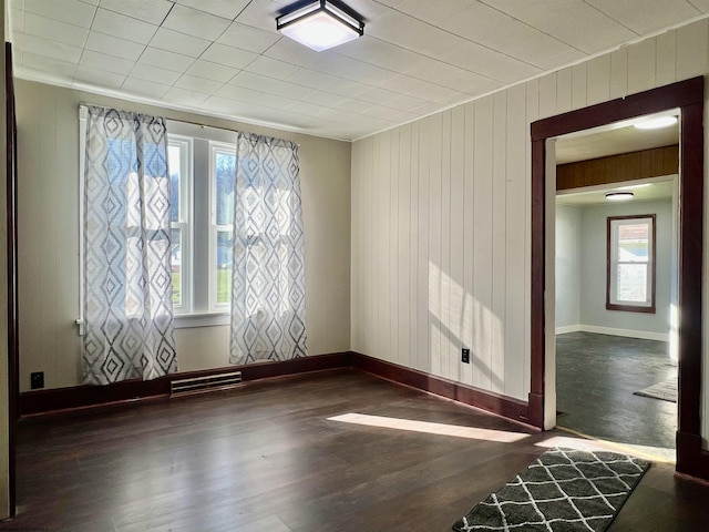 empty room featuring dark hardwood / wood-style flooring and wooden walls