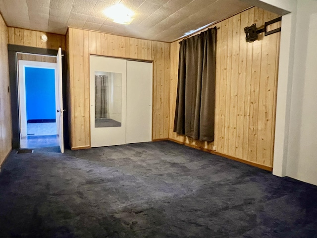 carpeted empty room featuring wood walls